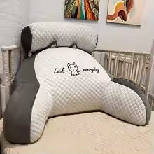 Gray and white pillow with text on a bed in a bedroom setting