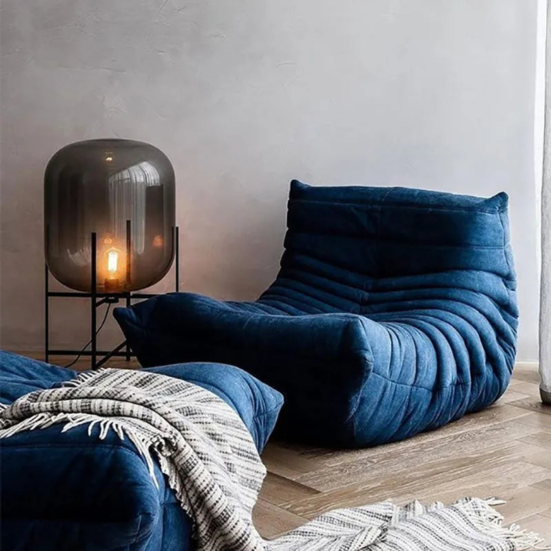 Blue lounge chair with a lamp and blanket in a room setting