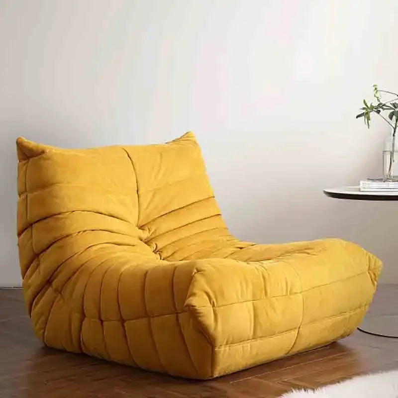 Yellow bean bag chair in a room with a table and plant.