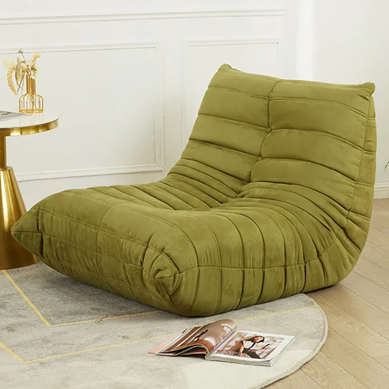 Green lounge chair in a room with a gold side table and magazine.