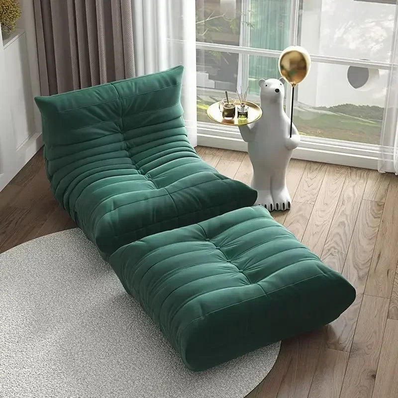 Green floor pillow in a room with a large window and decorative items.