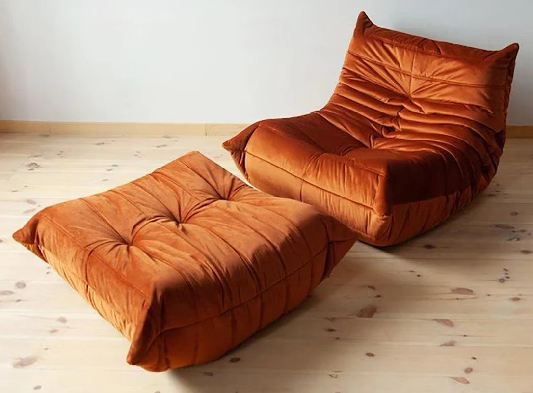 Orange lounge chair and ottoman on a wooden floor with a white wall background