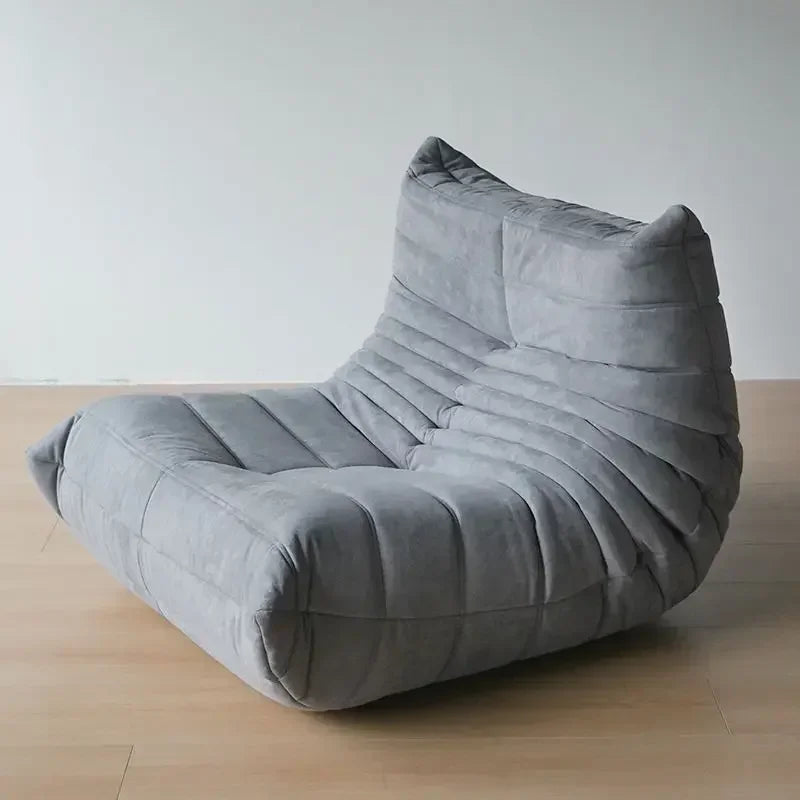 Gray cushioned chair on a wooden floor with a plain background