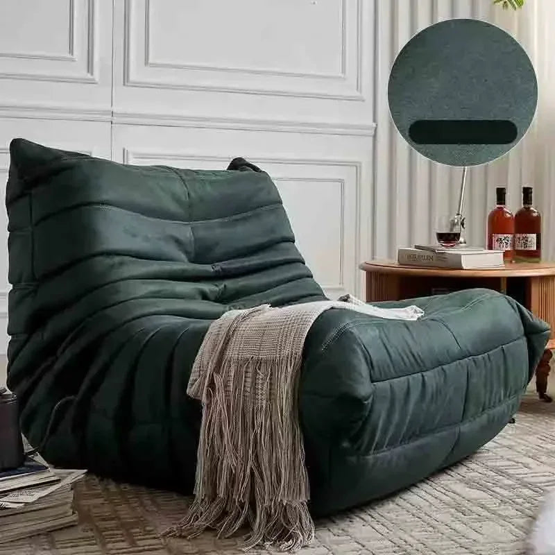 Green bean bag chair with a blanket in a room setting.