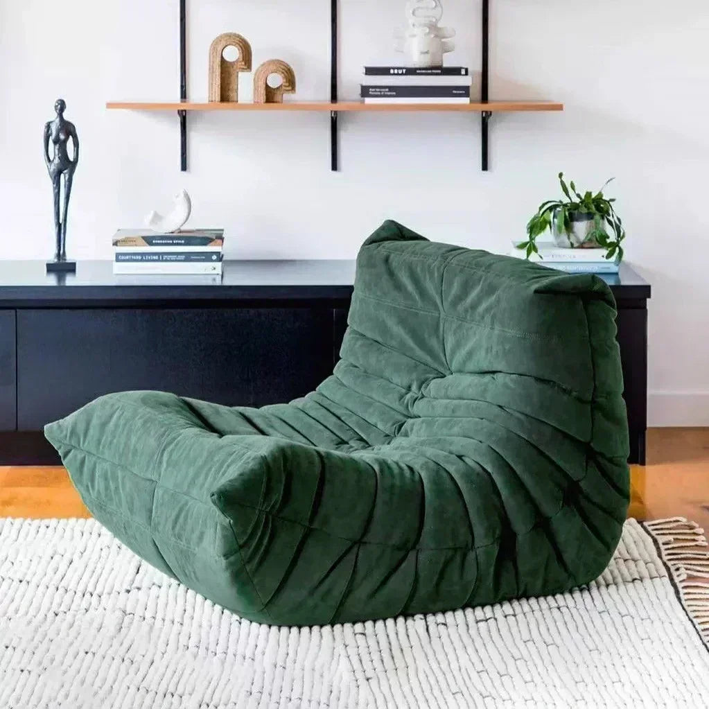 Green bean bag chair in a living room setting with a shelf and decor items.