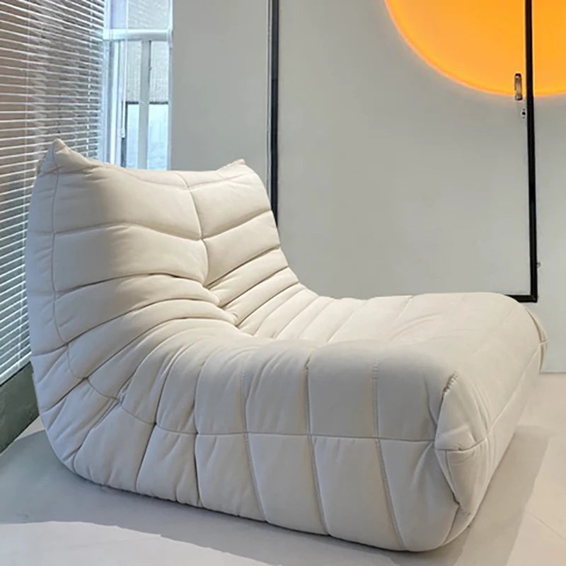 White textured bean bag chair in a minimalistic room with a large window and abstract wall art.