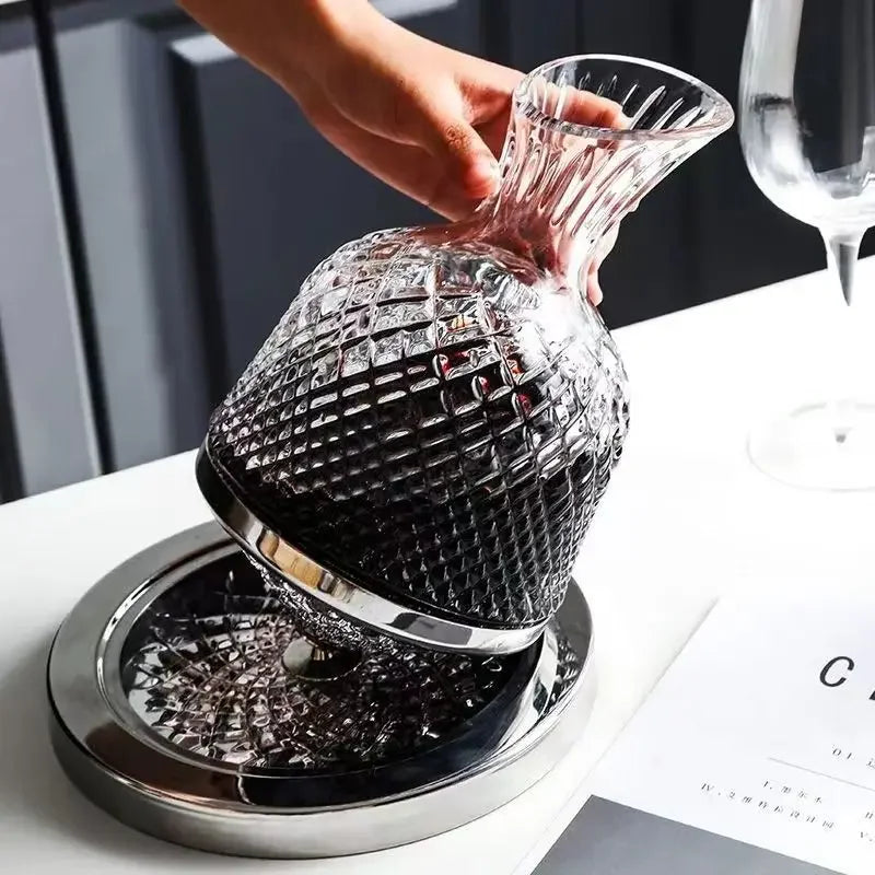 Clear glass decanter with a textured design on a metallic base, held by a hand.