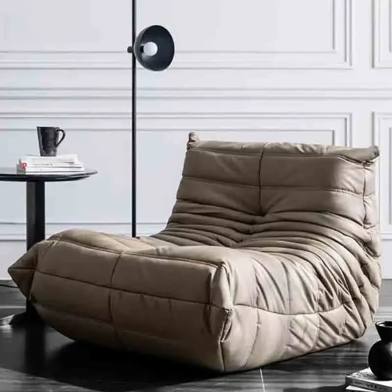 Beige bean bag chair in a modern room with a side table and lamp.