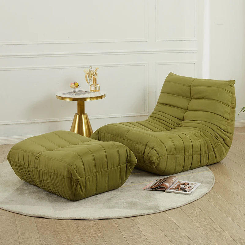 Green lounge chair and ottoman with a small round table in a room.