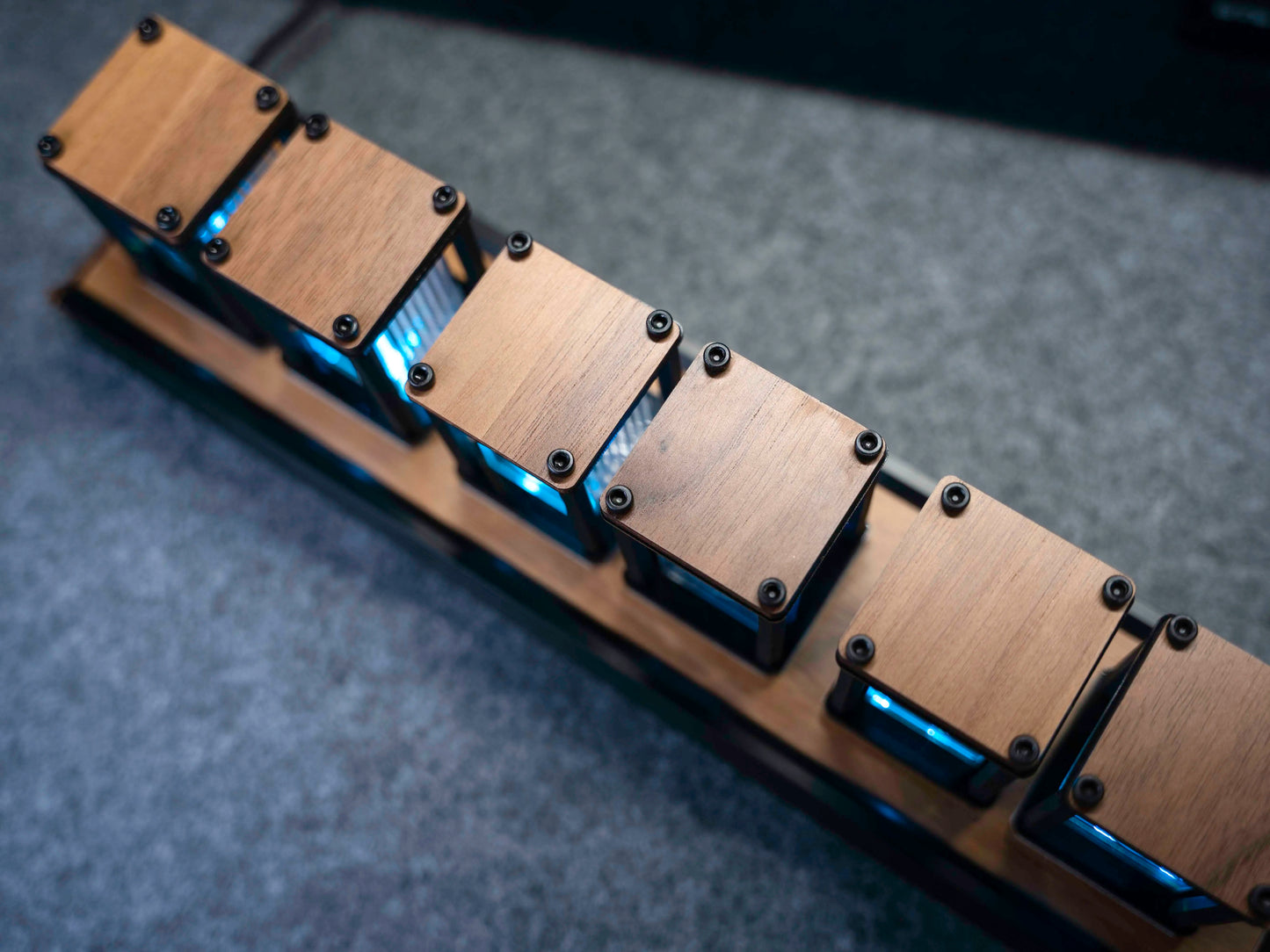 Wooden guitar neck with metal hardware on a gray surface